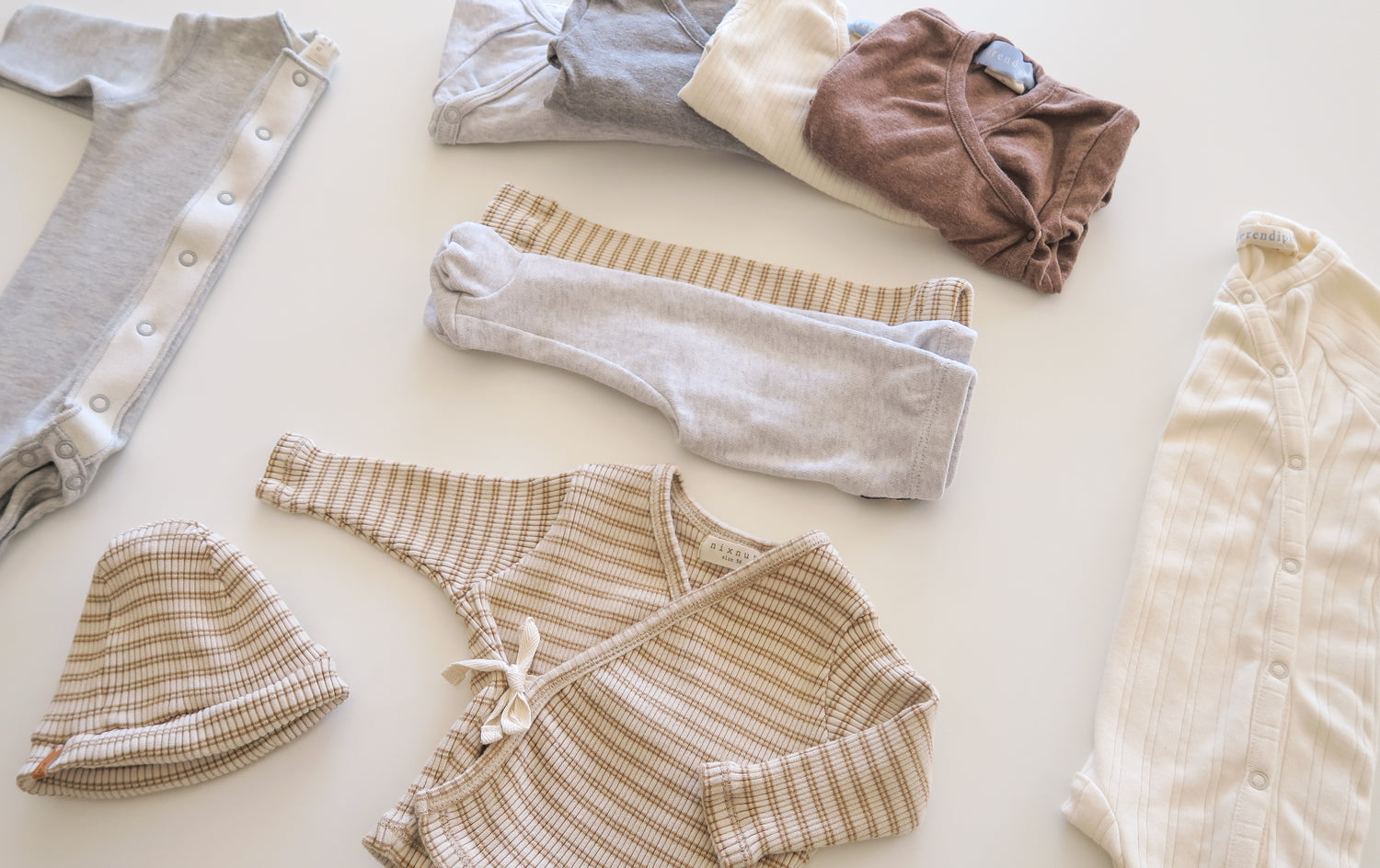Folded practical baby clothes from OiOiOi in organic cotton, striped and natural colors